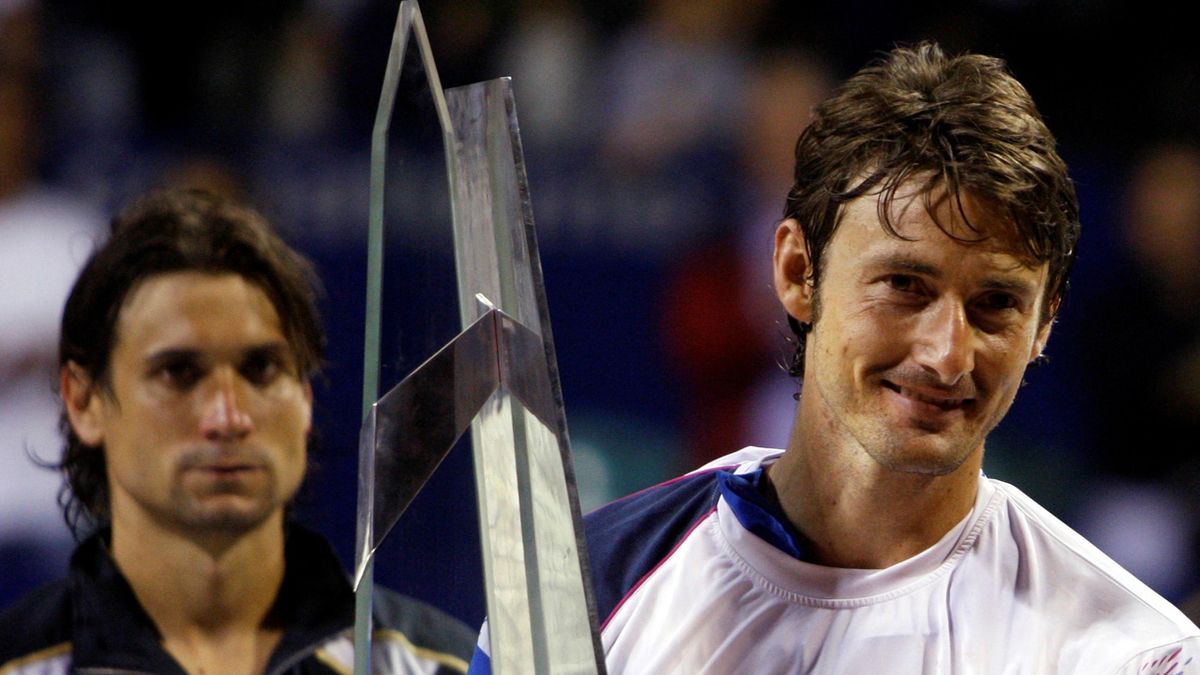 Juan Carlos Ferrero of Spain holds up the champion's trophy as compatriot David Ferrer (L) watches after their men's singles final tennis match at the ATP Buenos Aires Open