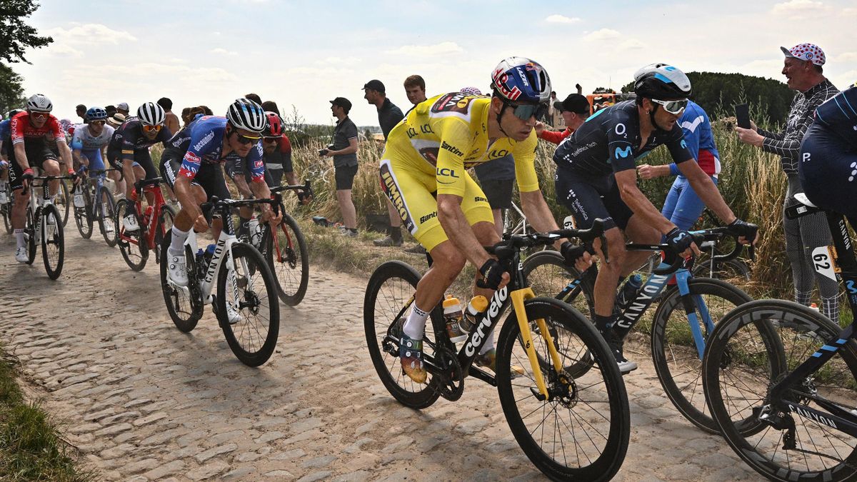 Jumbo-Visma team's Belgian rider Wout Van Aert (R) wearing the overall leader's yellow jersey cycles across a cobblestone sector with the pack of riders during the 5th stage of the 109th edition of the Tour de France