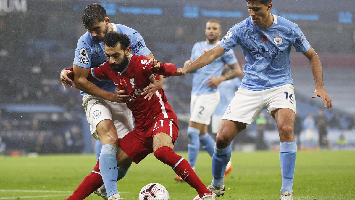 Mohamed Salah of Liverpool holds off Ruben Dias and Rodrigo of Manchester City during the Premier League match between Manchester City and Liverpool