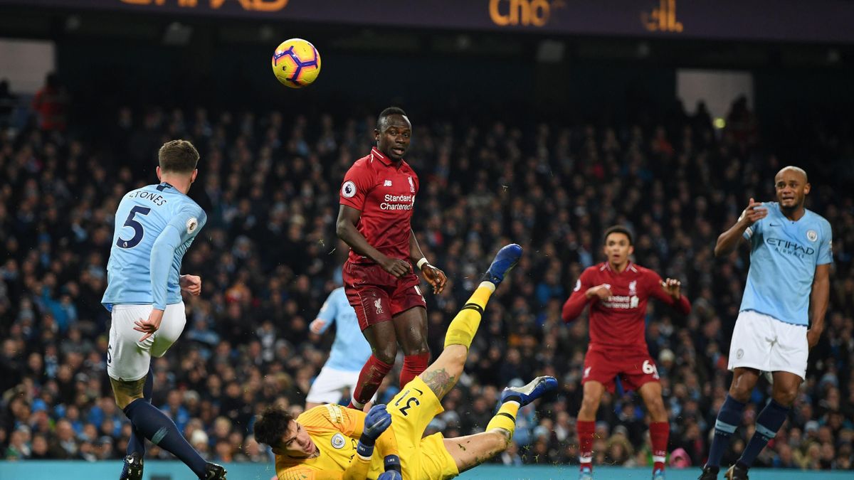 John Stones of Manchester City clears the ball as Ederson of Manchester City saves from Sadio Mane of Liverpool during the Premier League match between Manchester City and Liverpool FC at the Etihad Stadium on January 3, 2019 in Manchester, United Kingdom