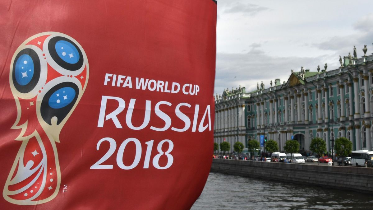 A picture taken on June 8, 2018 in Saint-Petersburg, shows a flag bearing the official logo of the upcoming Russia 2018 World Cup in front of the Winter Palace building housing the State Hermitage Museum