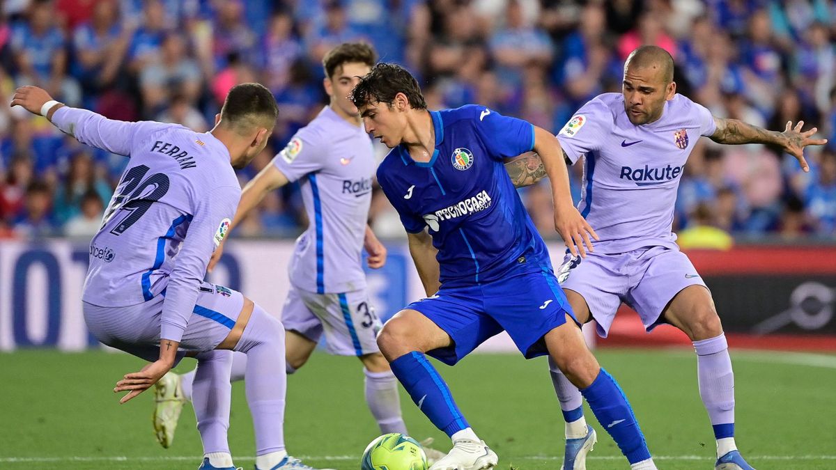 Getafe's Spanish midfielder Gonzalo Villar (C) fights for the ball with Barcelona's Spanish forward Ferran Torres (L) and Barcelona's Brazilian defender Dani Alves (R) during the Spanish league football match between Getafe CF and FC Barcelona at the Col.