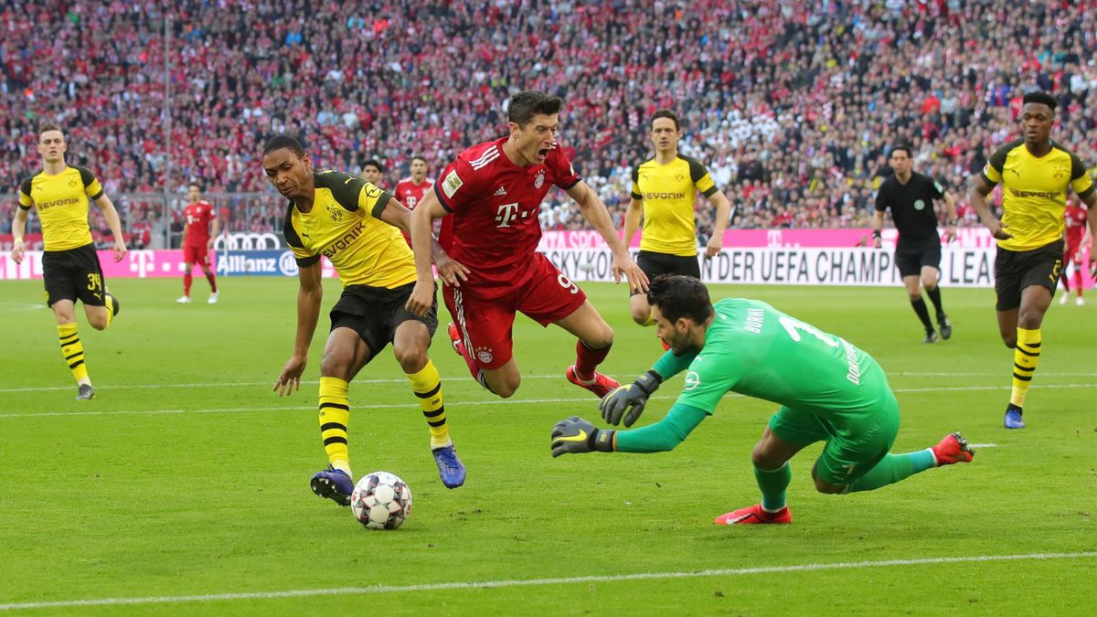 Robert Lewandowski of Bayern Munich is fouled by Abdou Diallo of Borussia Dortmund as Roman Buerki of Borussia Dortmund comes out to collect the ball during the Bundesliga match between FC Bayern Muenchen and Borussia Dortmund at Allianz Arena