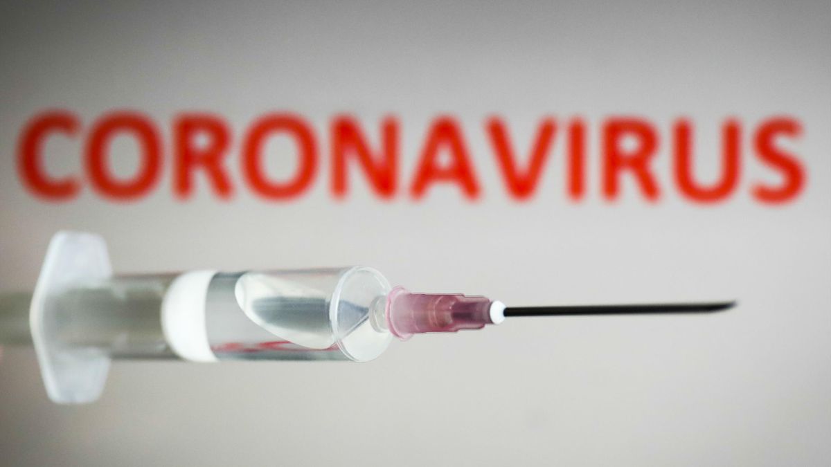 Medical syringe is seen with 'coronavirus' sign displayed on a screen in the background in this illustration photo taken in Poland on July 20, 2020. Early trial of the coronavirus vaccine developed by the Oxford University showed that it is safe and trigg