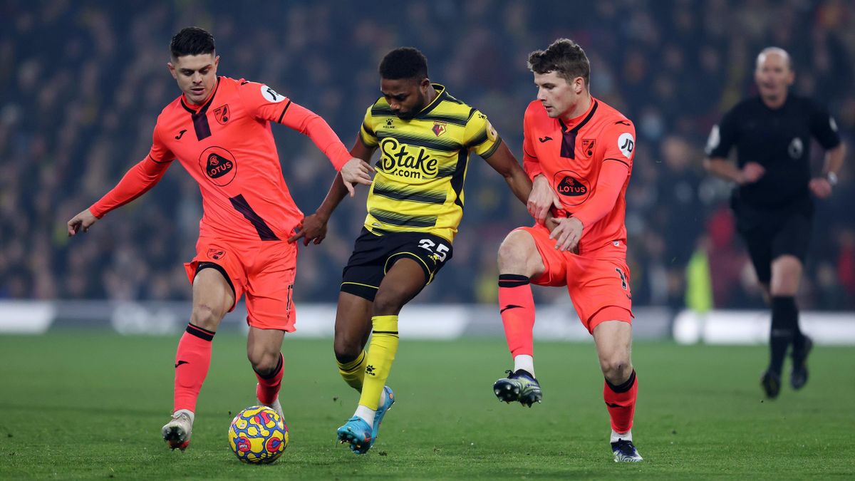 WATFORD, ENGLAND - JANUARY 21: Emmanuel Dennis of Watford takes on Milot Rashica of Norwich City (L) and Jacob Lungi Sorensen of Norwich City (r) during the Premier League match between Watford and Norwich City at Vicarage Road on January 21, 2022 in Watf