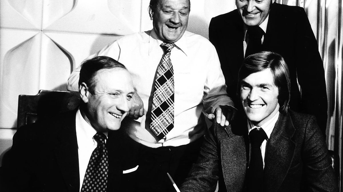 Kenny dalglish, semnând contractul cu Liverpool, în prezența  managerului Bob Paisley, a președintelui John Smith și a secretarului general Peter Robinson (1977)