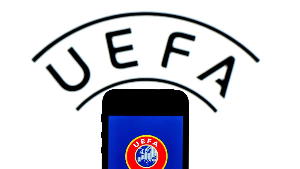 In this photo illustration a UEFA logo seen displayed on a smartphone with a UEFA logo in the background.