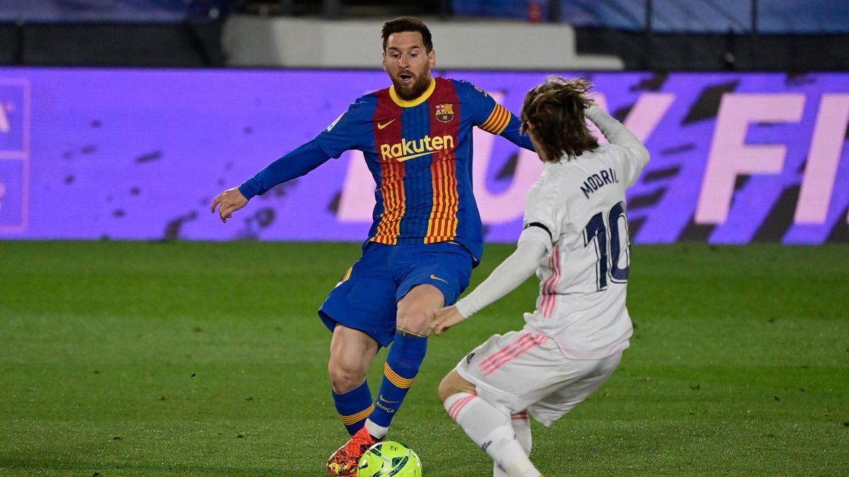 Real Madrid's Croatian midfielder Luka Modric (R) challenges Barcelona's Argentinian forward Lionel Messi during the "El Clasico" Spanish League football match between Real Madrid CF and FC Barcelona at the Alfredo di Stefano stadium in Valdebebas, on the