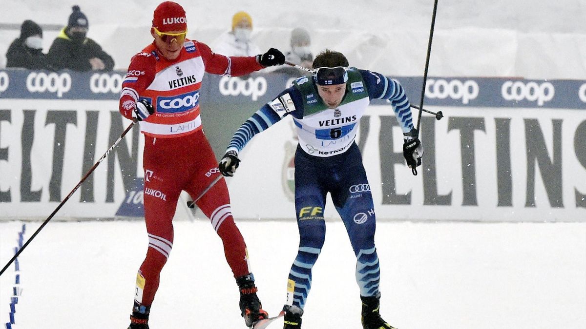 Russia's Alexander Bolshunov (L) competes with Finland's Joni Maeki in the final meters, slashing Maeki with his stick, during the men's Cross Country relay 4x7,5km