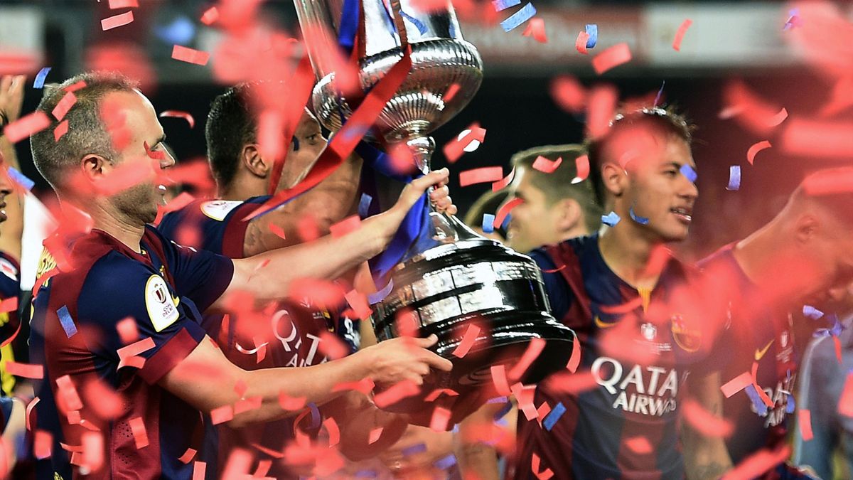 Barcelona's midfielder Andres Iniesta (L) celebrates with the trophy at the end of the Spanish Copa del Rey