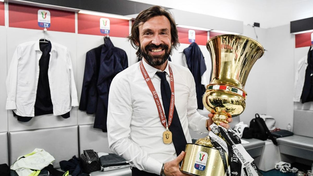 Andrea Pirlo mostra sorridente la Coppa Italia vinta con la Juventus nella stagione 2020-21