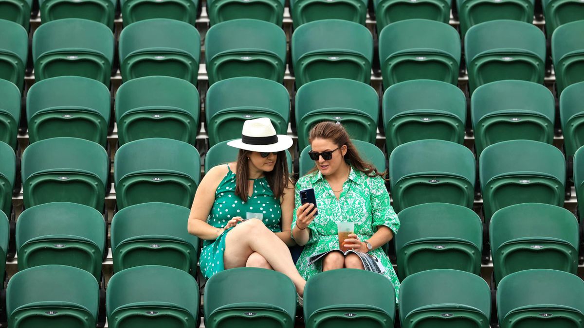 Two women sit in rows of empty seats during Day One of The Championships Wimbledon 2022 at All England Lawn Tennis and Croquet Club on June 27, 2022 in London, England