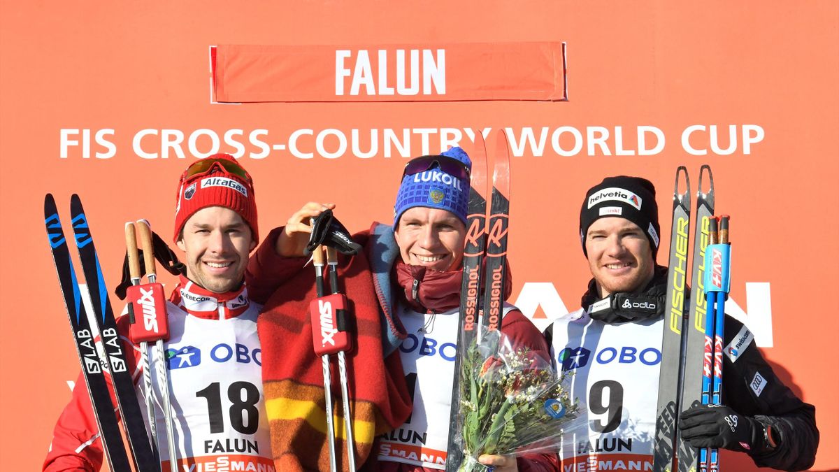 Second-placed Alex Harvey of Canada, winner Alexander Bolshunov of Russia and third-placed Dario Cologna of Switzerland celebrate on the podium.