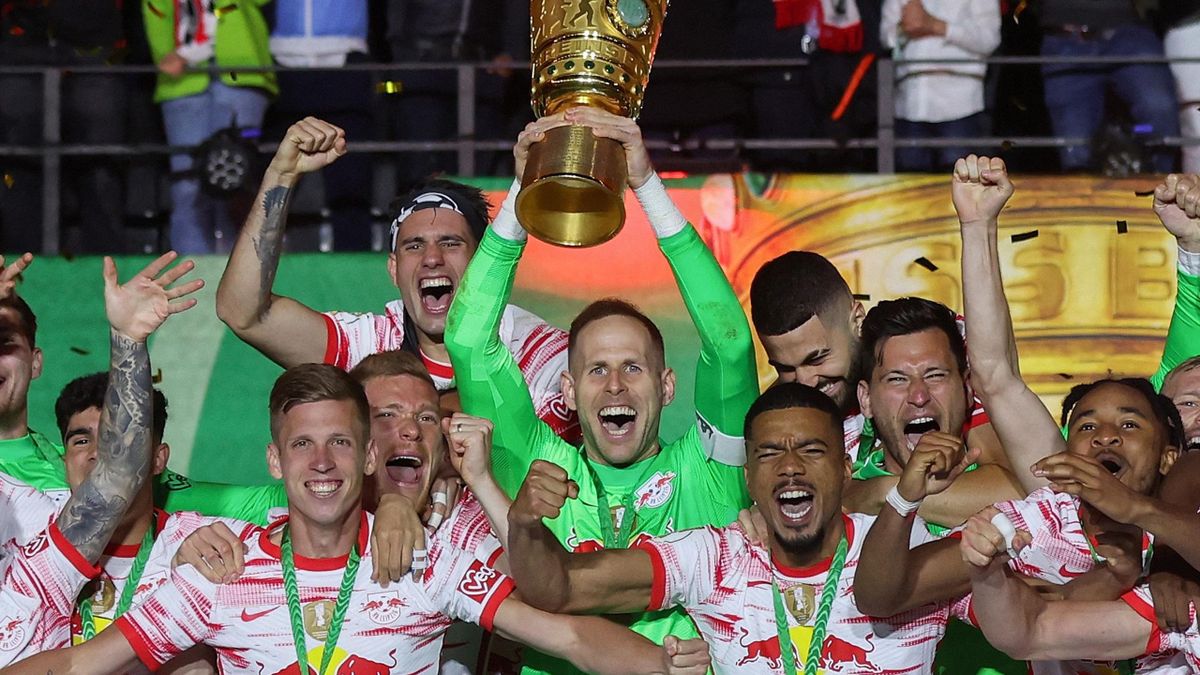 Leipzig's Hungarian goalkeeper Peter Gulacsi (C) and his teammates celebrate with the trophy after the German Cup final football match between SC Freiburg and RB Leipzig at the Olympic Stadium in Berlin on May 21, 2022.
