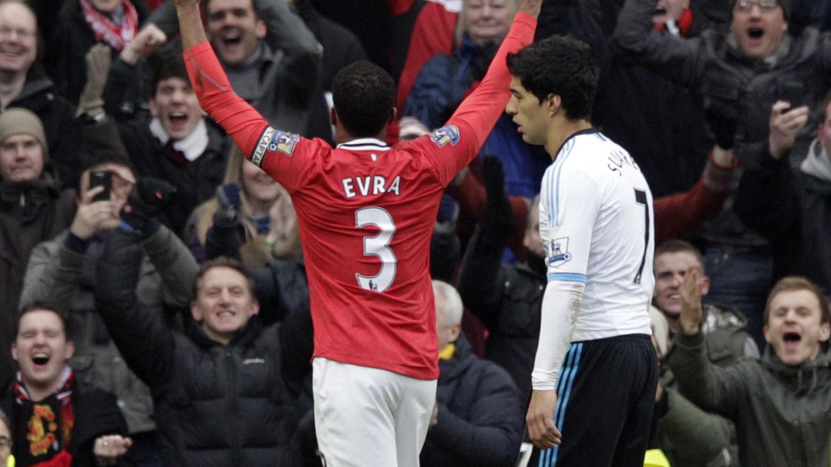 Manchester United's Patrice Evra celebrates victory as Liverpool's Luis Suarez walks off