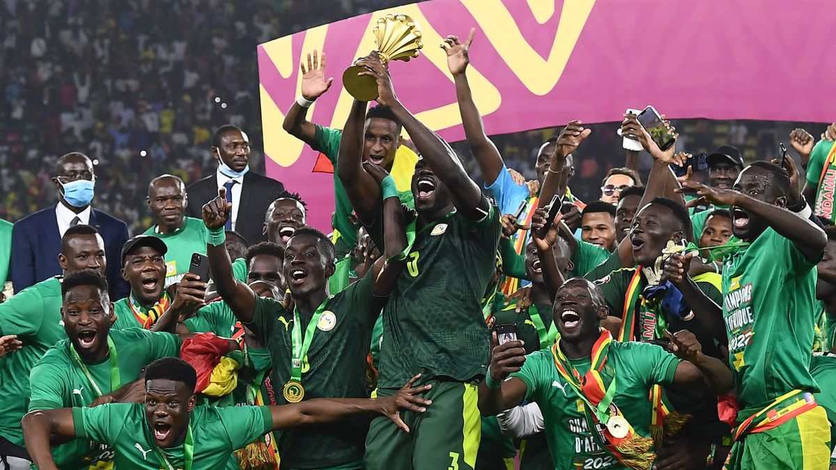 Senegal's defender Kalidou Koulibaly (C) holds the trophy as he celebrates with teammates after winning the Africa Cup of Nations (CAN) 2021 final football match between Senegal and Egypt at Stade d'Olembe in Yaounde on February 6, 2022.
