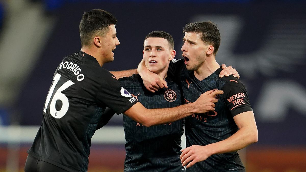 Phil Foden of Manchester City celebrates with team mates (L - R) Rodrigo and Ruben Dias after scoring their side's first goal during the Premier League match between Everton and Manchester City at Goodison Park on February 17, 2021 in Liverpool, England.