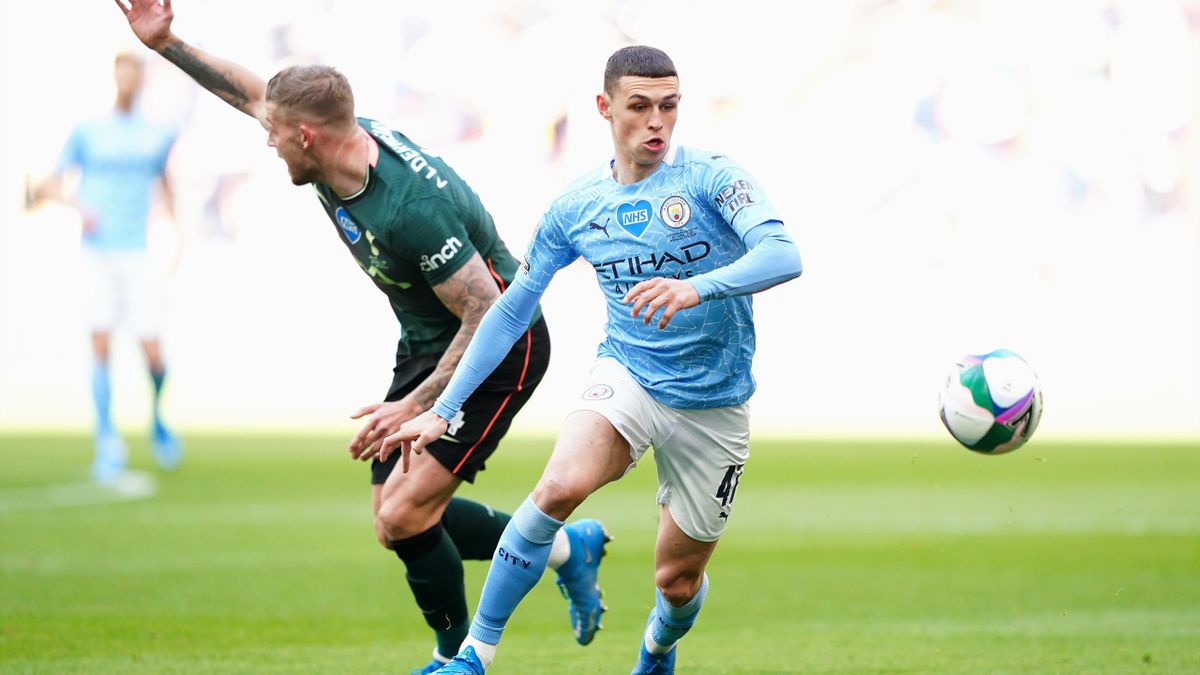 Phil Foden of Manchester City runs with the ball as Toby Alderweireld of Tottenham Hotspur reacts