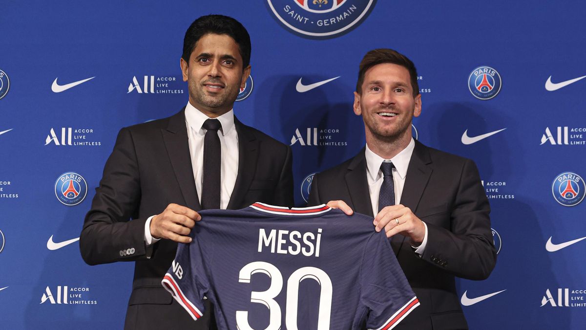 Lionel Messi poses with his jersey next to President Nasser Al Khelaifi