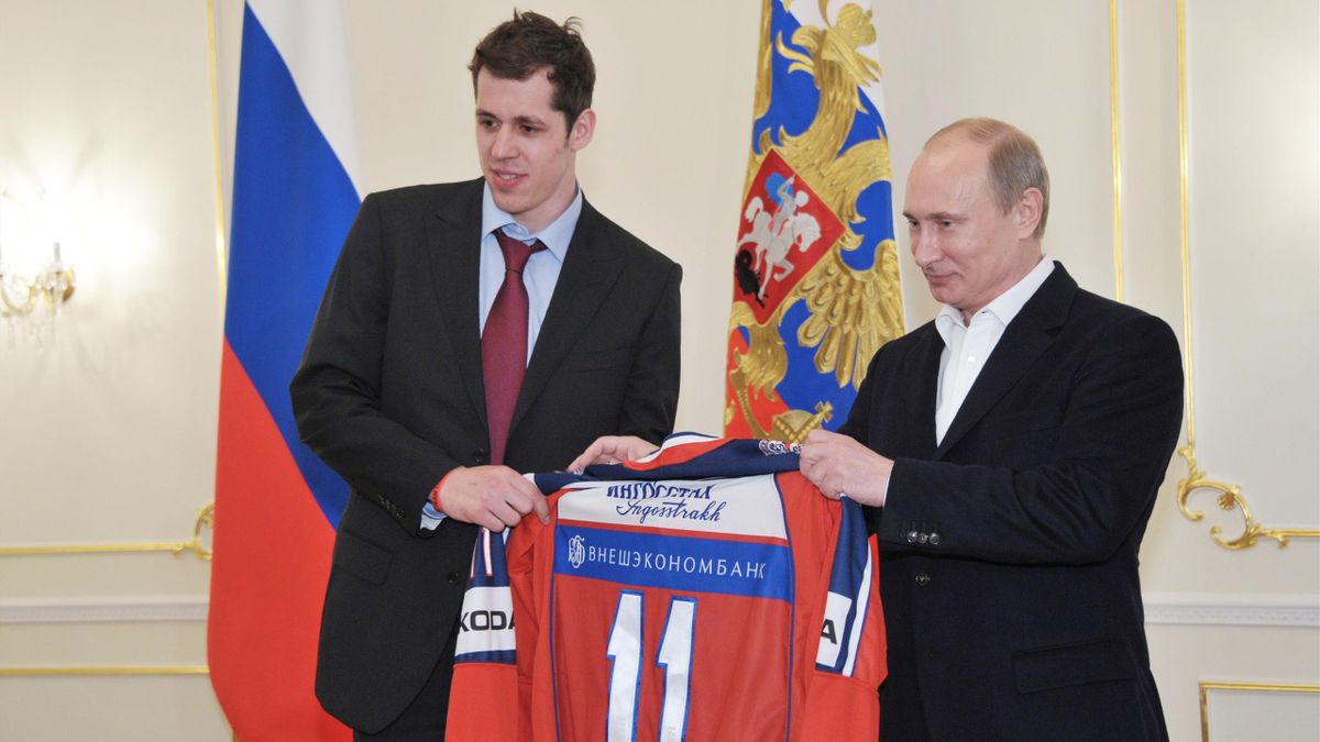 Russian President Vladimir Putin (R) holds sa jersey alongside Russian hockey player Yevgeny Malkin