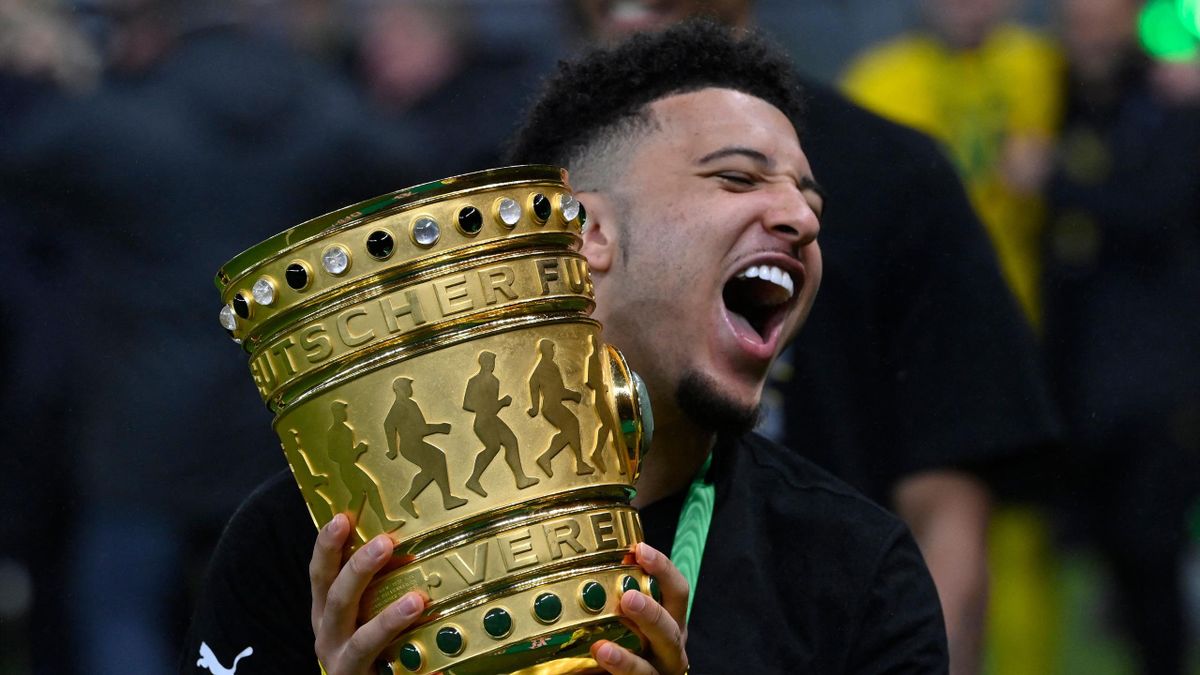 Dortmund's English midfielder Jadon Sancho holds the trophy after the ceremony after the German Cup (DFB Pokal) final football match RB Leipzig v BVB Borussia Dortmund, in Berlin on May 13, 2021.