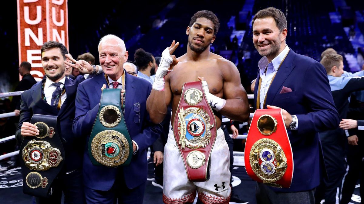 Anthony Joshua poses for a photo with the IBF, WBA, WBO & IBO World Heavyweight Title belts with Eddie Hearn and Barry Hearn