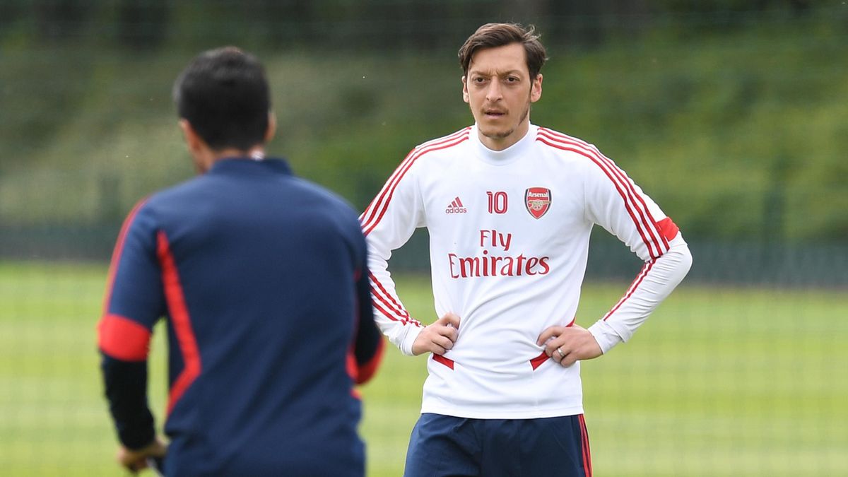 Mesut Ozil listens to Arsenal Head Coach Mikel Arteta during a training session