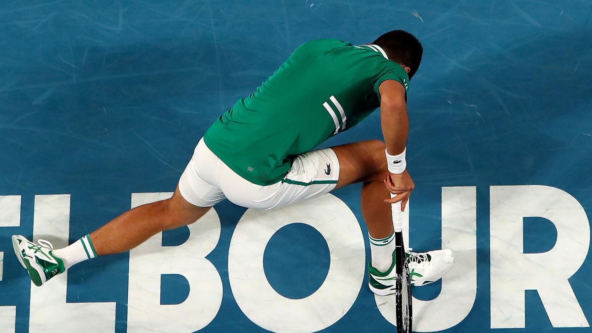 Serbia's Novak Djokovic falls on the court in an attempt to hit a return against Taylor Fritz of the US during their men's singles match on day five of the Australian Open tennis tournament in Melbourne on February 12, 2021.