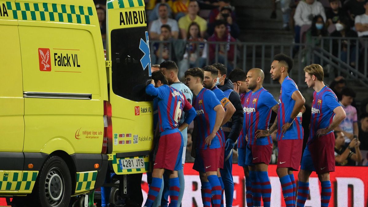 Barcelona's players stand near the ambulance during the evacuation of Uruguayan defender Ronald Araujo after an injury, during the Spanish league football match between FC Barcelona and RC Celta de Vigo at the Camp Nou stadium in Barcelona on May 10, 2022