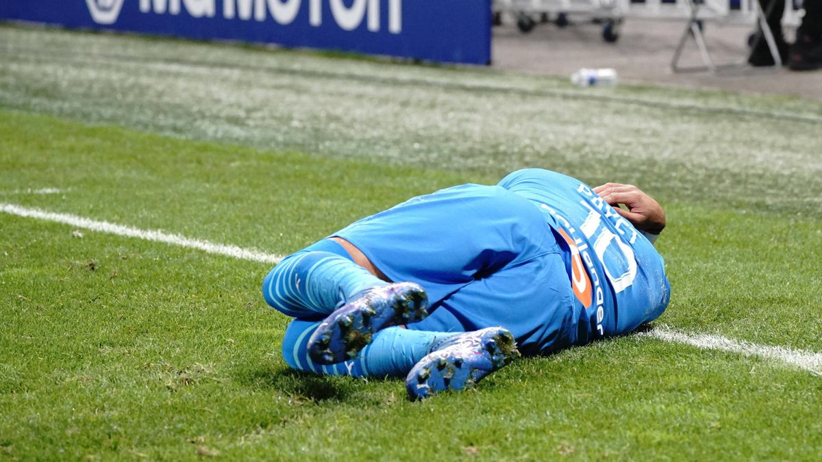 Dimitri Payet allongé sur la pelouse du Groupama Stadium après avoir reçu une bouteille dans la tête lors du match entre l'OL et l'OM, le 21 novembre 2021.