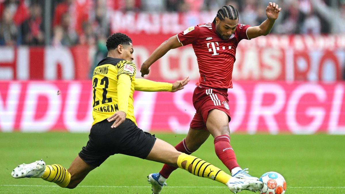 Jude Bellingham of Borussia Dortmund challenges Serge Gnabry of Bayern Munich during the Bundesliga match between Bayern Munich and Borussia Dortmund at Allianz Arena on April 23, 2022 in Munich, Germany