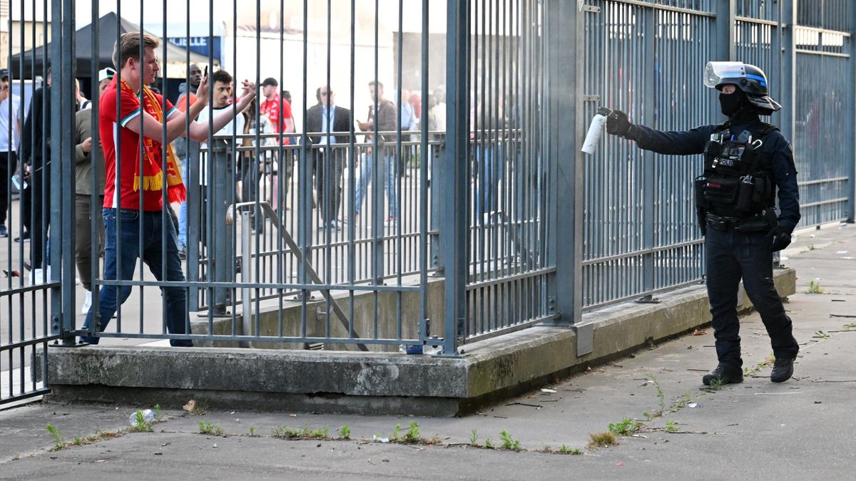 A Liverpool fan interacts with a French police officer